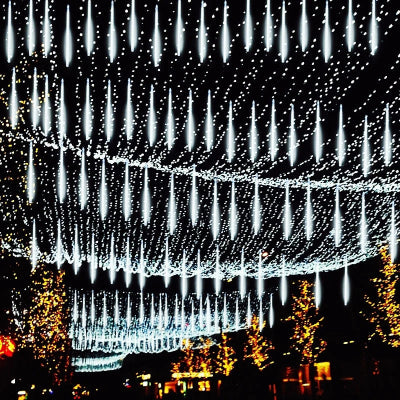 Guirlande LED Météore Jardin allumée lumière blanc froid suspendue entre arbres dans jardin décoré multiples guirlandes