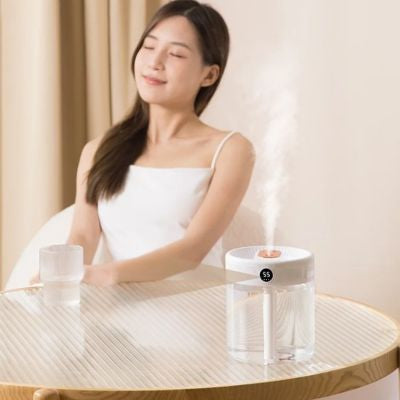 Humidificateur d air  Transparent posé sur une table ronde profité de l'effet bénéfique par une jeune fille