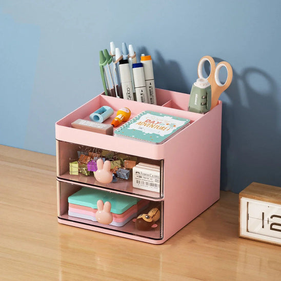 Organisateur de bureau Premium rose rempli fournitures scolaires placé sur bureau adossé mur couleur verte