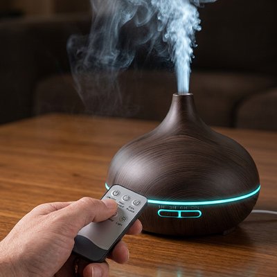 Humidificateur d air​ noir posé sur la table dans salle de séjour main tenant la télécommande